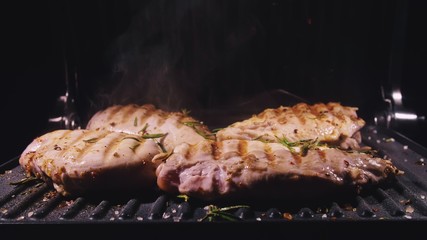 Delicious juicy meat steak cooking on the grill. Cook grilling fresh chicken breast. Fry chicken fillet on electric roaster. Slow motion.