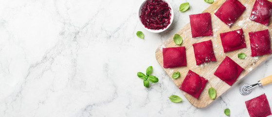 Beetroot ravioli stuffed with baked beets on a wooden board on a marble background. The process of...