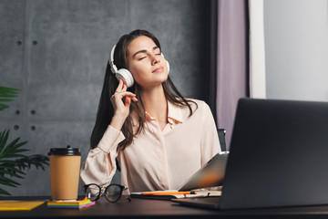 Girl in headphones enjoying music in front of laptop. Great sound quality and design of wireless...