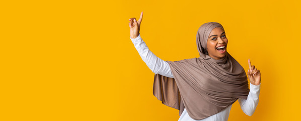 Cheerful Afro Muslim Girl In Hijab Having Fun Over Yellow Background