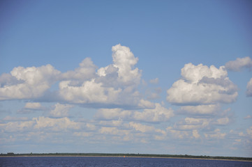 Fluffy cumulus clouds over a pond in the summer. sunny day