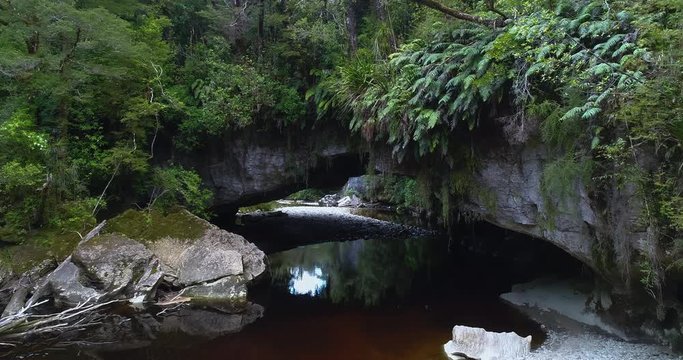 4k forward tracking and ascending aerial view of Moria Gate Arch on the Oparara River in the Oparara Basin Arches situated in the Kahurangi National Park,Karamea,South Island New zealand