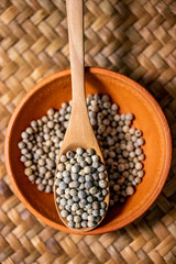 close-up of white pepper on wooden spoon in earthen bowl, most important flavorings in East Asia.