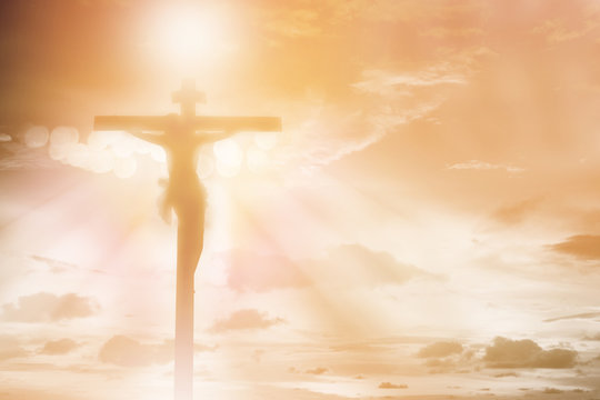 silhouette Jesus Christ crucifixion on cross over orange sunset light background, prayer and praise religion concept