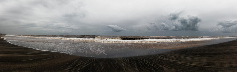 Stormy weather on the beach, the waves crash on the shore leaving their mark, overcast sky with...