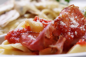 Cooked Penne macaroni with tomato sauce, parmesan and prosciutto