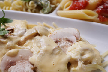 A white plate with three types of cooked  pasta