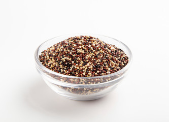 Mix of quinoa seeds in glass bowl, white background