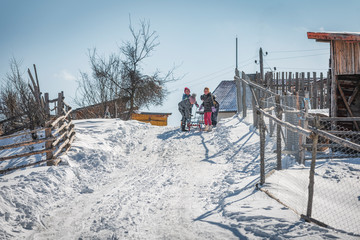 Grashevo village, Rhodope mountains, Bulgaria - 02.08.2020: Little children having fun riding ice slide in winter