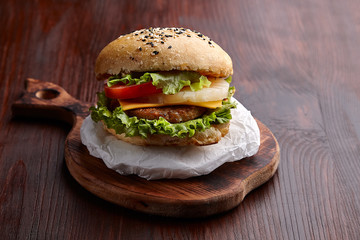 Appetizing burger on the board on a dark wooden table