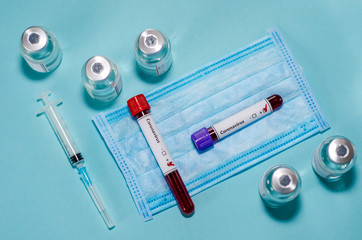 Test tube with positive Coronavirus test blood sample and vaccine bottle in the medical laboratory.