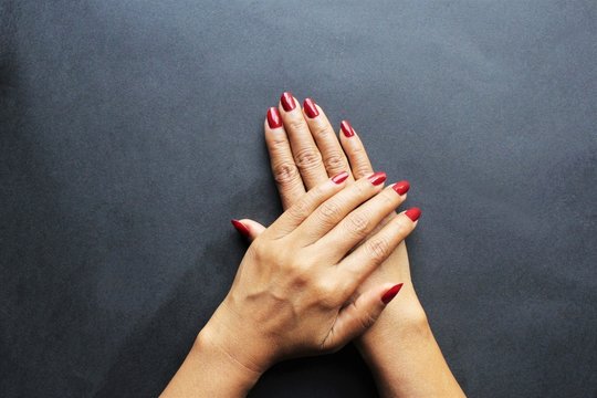 Woman hand red nail polish showing hands left hand on top of the right photo isolate top view black background copy space