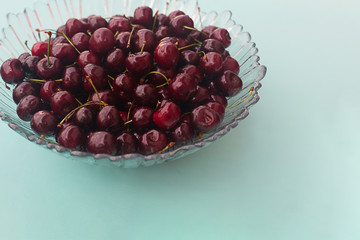 Glass plate with fresh fragrant cherry on a light background.