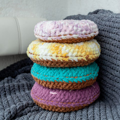 Colored decorative pillows in the form of donuts on a gray plaid background