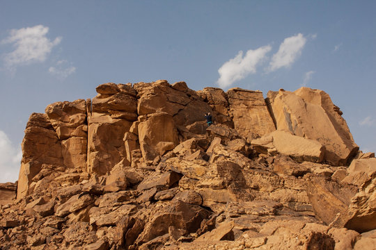 A tourist taking photos of Musayqirah Petroglyphs (Grafiti Rock), Qaryat Al Asba, Saudi Arabia