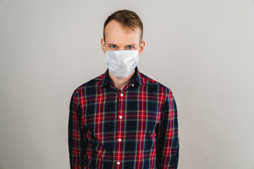 A man in a medical mask stands on a white background. The man looks at the camera. Protection from the virus. Protection against coronavirus. Health problem