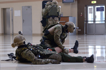 Soldier of police strike force giving first aid to his wounded fellow, others took position