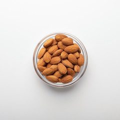 Peeled almonds in glass bowl on white background
