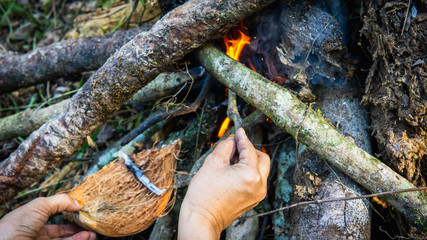 Close up view of hand making a campfire using the dried tree branches.