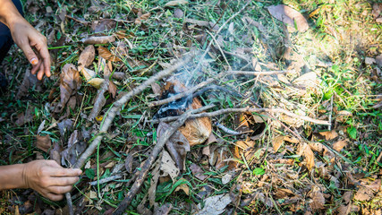Making a fire using a hot coal from dried tree branches and coconut fiber on the ground.