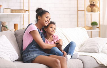 Cheerful african sisters embracing at home, free space