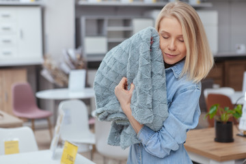 Young beautiful woman cuddling to a soft blanket, shopping for home goods at furnishings store, copy space