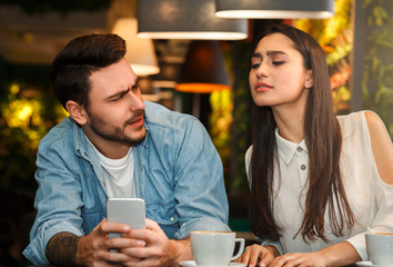 Girlfriend Reading Boyfriend's Messages While He Texting Sitting In Cafe