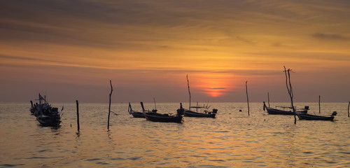 view seaside evening of fishing boats floating in the sea with orange sun light in the sky background, sunset at Klong Hin Beach, Ko Lanta island, Krabi, southern of Thailand.