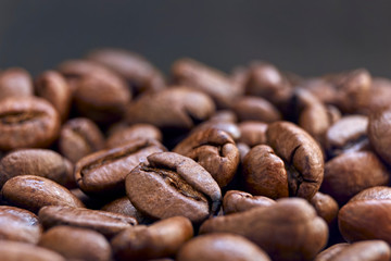 Closeup of brown roasted coffee beans against a black background. Image with copy space and selective focus.	