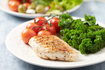 Grilled Chicken Breast with roasted Cherry Tomatoes. Bright wooden background