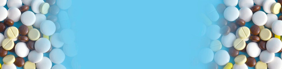 Close up image of a lot of different medical pills, capcules, tablets on blue background. Health care or dangerous drugs addiction concept. Banner.