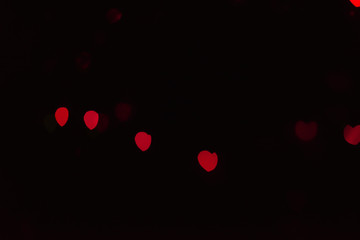 Abstract blur defocused background black, red lights highlights, bokeh hearts, soft focus