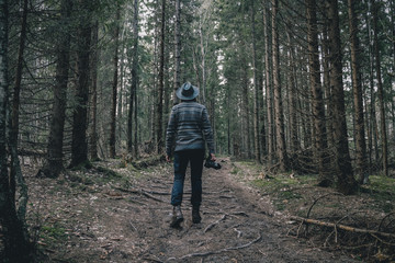 Obraz premium Man traveler with photo camera walking in the dark forest. Travel Lifestyle and Adventure concept.