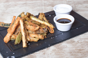 Plate of natural potatoes with sauces on black stone plate