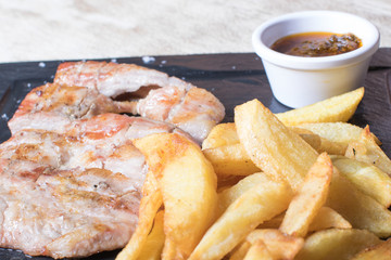 beef steak with potatoes and sauce on black stone plate