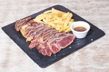 beef steak with potatoes and sauce on black stone plate