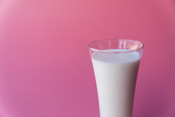 Fresh milk in  luxury tall glass for breakfast on pastel pink background.