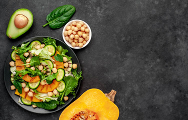 plate of pumpkin salad, avocado, cucumber, chickpea, lettuce on a stone background with copy space for your text