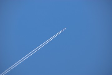 Aircraft flying through the sky blue, Condensing traces in the background.