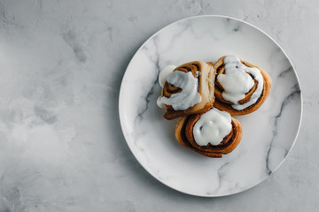 cinnamon bun with white chocolate on a plate, on a concrete background with a cloth