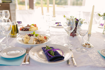 Festive setting of the Banquet table. A purple napkin lies on a white plate