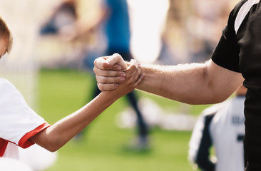 Soccer football kids player and junior team coach congratulating after the match. Greeting after soccer game. Trainer and child shaking hands after playing tournament match