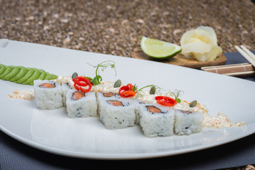 Traditional rolls with fish and rice on a white plate with sauce and wasabi. Japanese food.