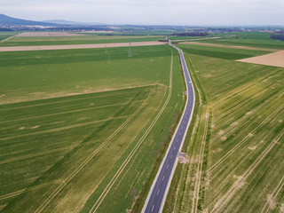 Aerial view on the highway between the green fields