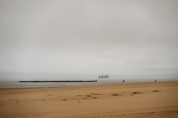 shore coast with oil tankers on the sea in bad weather with stormy clouds