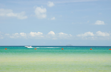 Speedboat sailing along the beach on a sunny day.