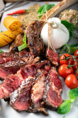 Sliced Tomahawk steak Grilled in Italian style with burata cheese, Basil and tomatoes on a wooden Board