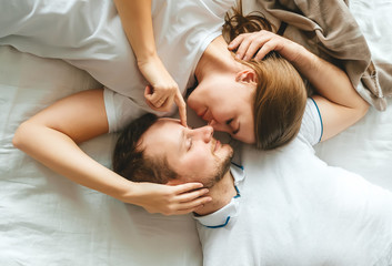 Top view of beautiful young couple lying face to face while spending time in the bedroom.