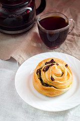 French bread with a Cup of black coffee on a linen tablecloth. French bread with coffee for Breakfast. Wholesome breakfast. Morning meal. Baking with raisins. Sweet bun.