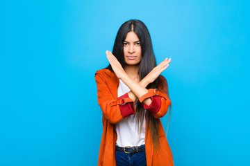 young pretty latin woman looking annoyed and sick of your attitude, saying enough! hands crossed up...